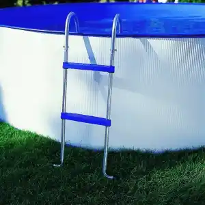 Above-ground pool with a blue rim and silver ladder resting on green grass beside it.