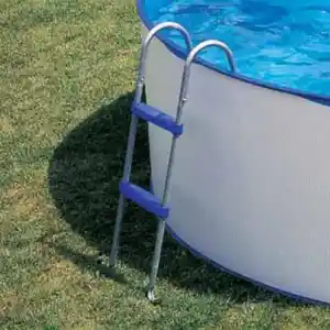 Above-ground pool with a blue ladder resting on the grassy yard beside the pool edge.