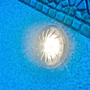 Circular recessed light on a blue textured surface with a metal grate pattern above.