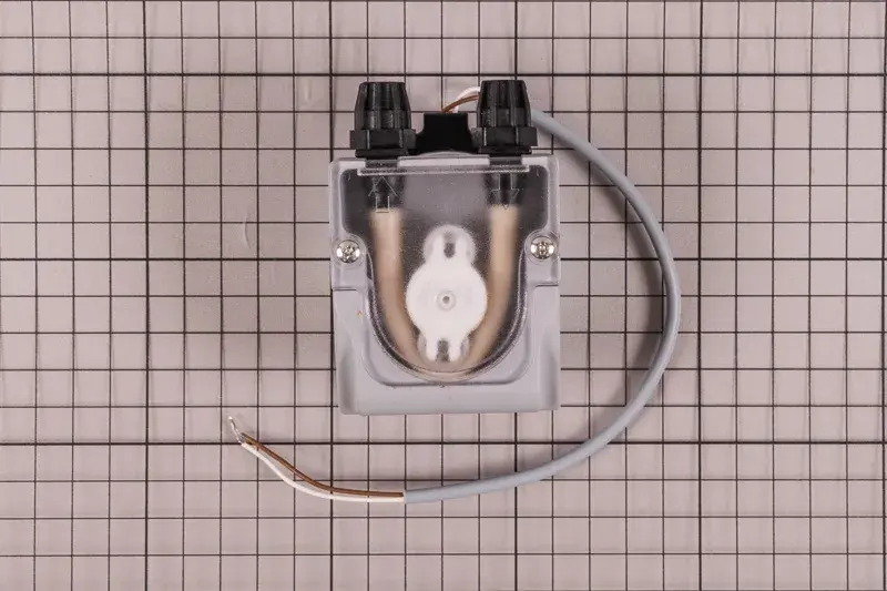clorador-salino-gre-swc-conectado-todo-en-uno-ph-1 | PisciManía Small gray plastic valve/solenoid assembly with a clear cover, two black adjustment knobs, exposed copper tubes inside, on a grid background.