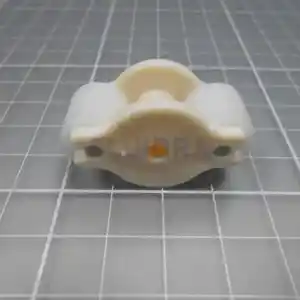 clorador-salino-gre-swc-conectado-todo-en-uno-ph-2 | PisciManía Small cream-colored plastic clamp/bearing holder with two entering holes and a central circular boss, resting on a gray grid cutting mat.